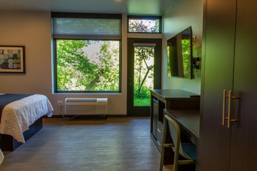 a bedroom with a bed and two windows in it at Watershed Hotel in Sheboygan