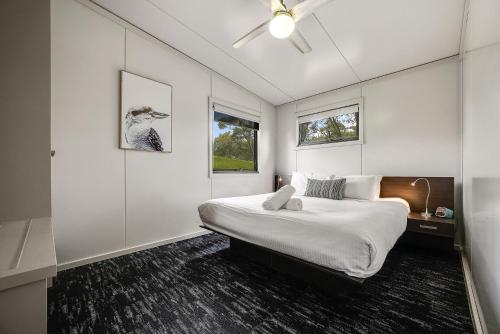a white bedroom with a bed and a window at Ecocrackenback 3 Sustainable chalet close to the slopes in Crackenback