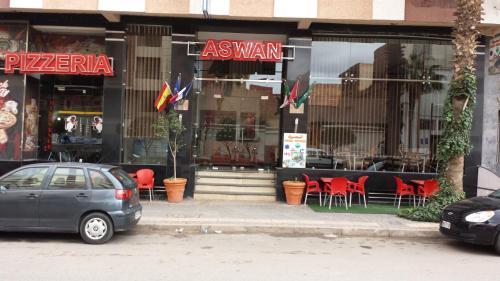 a car parked in front of a restaurant with red chairs at Hotel Aswan in Oujda