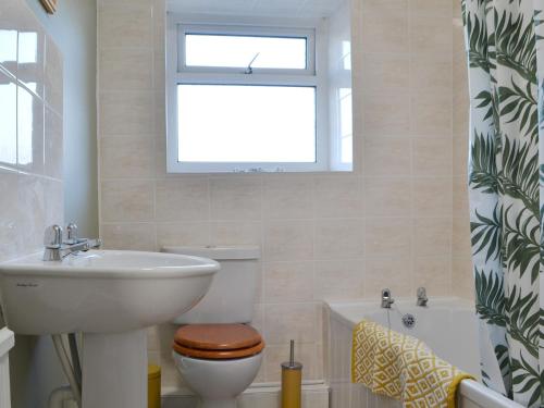 a bathroom with a toilet and a sink and a window at The Farmhouse At Lane Foot in Tallentire