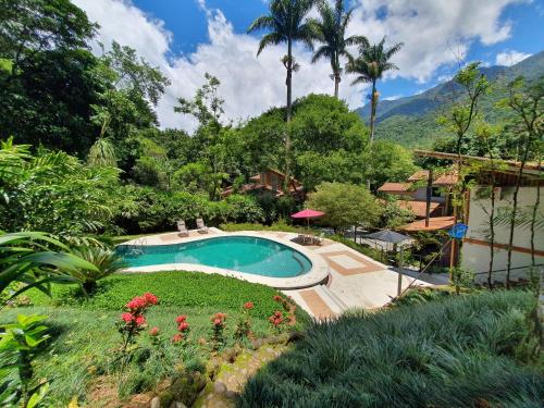 einen Pool in einem Garten mit Blumen und Palmen in der Unterkunft Pousada Tekoá Indiana in Cachoeiras de Macacu