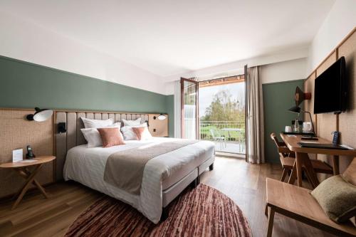um quarto com uma cama, uma secretária e uma televisão em Best Western Plus l'Orée Paris Sud em Saulx-les-Chartreux