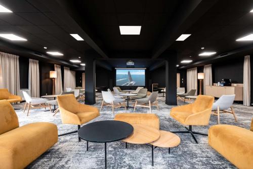 uma sala de espera com cadeiras e mesas e um ecrã em Best Western Plus l'Orée Paris Sud em Saulx-les-Chartreux