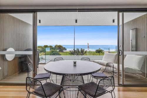 a dining room with a table and chairs and a view of the ocean at Louttit Bay Apartment 1 in Lorne