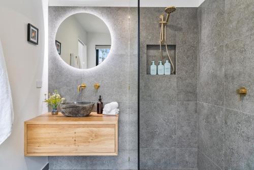 a bathroom with a shower with a sink and a mirror at The Hide On Cloudy in Lunawanna