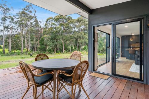 a dining room with a table and chairs on a deck at The Hide On Cloudy in Lunawanna