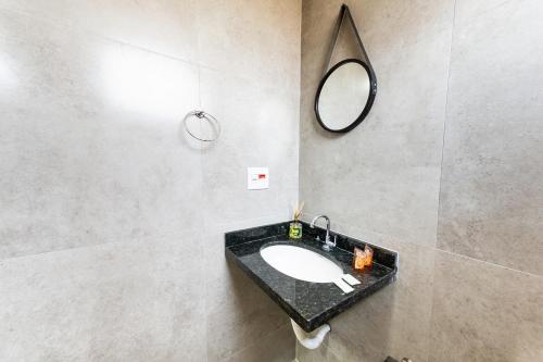 a bathroom with a sink and a mirror on the wall at Jahu Center Plaza Flats in Jaú