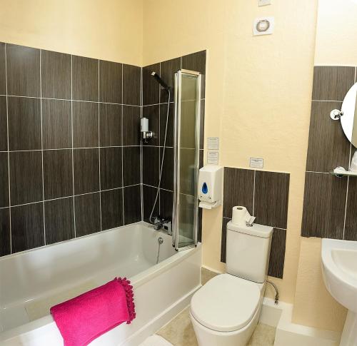 a bathroom with a toilet and a tub and a sink at Villa Mentone Hotel in Shanklin