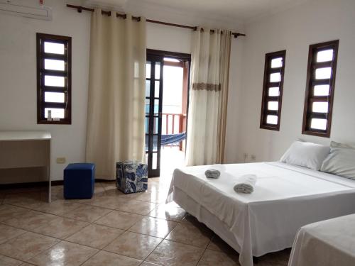um quarto com uma cama branca e uma casa de banho em Casa da Fê em São Sebastião