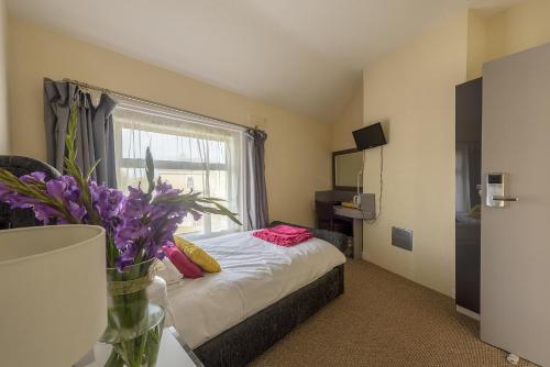 a bedroom with a bed and a window with purple flowers at Villa Mentone Hotel in Shanklin
