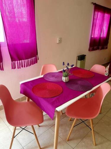 mesa púrpura con sillas rosas y cortinas rosas en Monoambiente moderno amplio x día en Neuquén