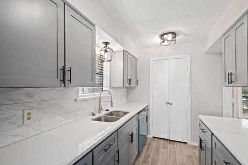 eine weiße Küche mit einem Waschbecken und weißen Schränken in der Unterkunft Modern & luxurious & pool & SPA & 5 bedroom in McKinney