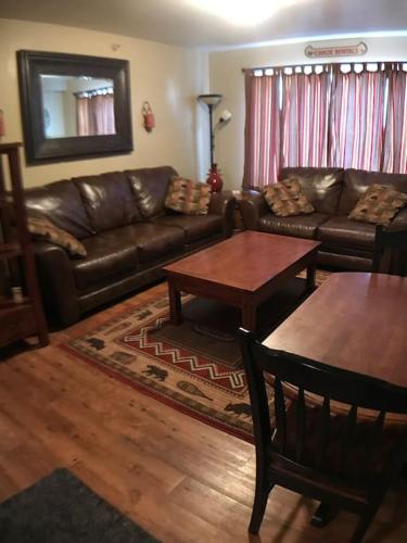 a living room with a leather couch and tables at Rustic 2 BR Mountain View-walk to resort in Big Sky