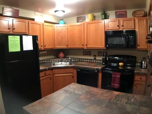 una cucina con armadi in legno e frigorifero nero di Rustic 2 BR Mountain View-walk to resort a Big Sky