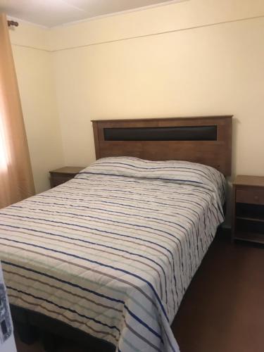 Un dormitorio con una cama con una manta a rayas. en Casa a 5 min de Avda del Mar en La Serena