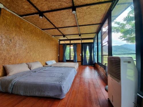 - une chambre avec un grand lit dans une pièce dotée de fenêtres dans l'établissement Baanhatsompaen homestay, à Ranong