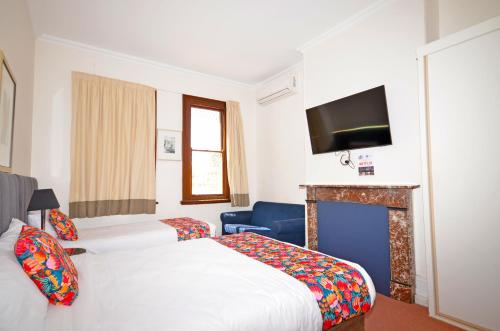 una camera d'albergo con due letti e un camino di The Hallows Accommodation a Bathurst