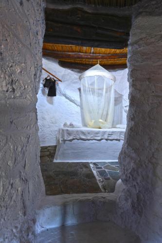 a window in a stone building with a large vase at Aspros Potamos in Makry Gialos