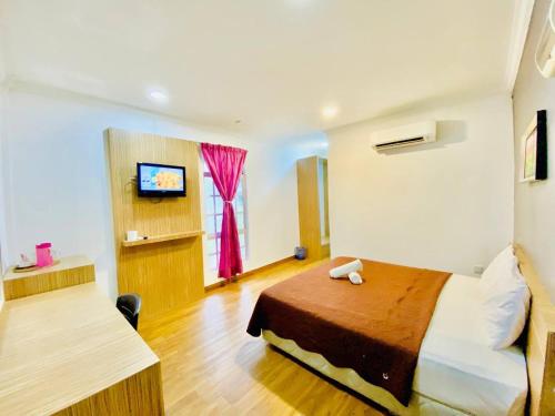 a hotel room with a bed and a television at Landcons Hotel & Resort in Pantai Cenang