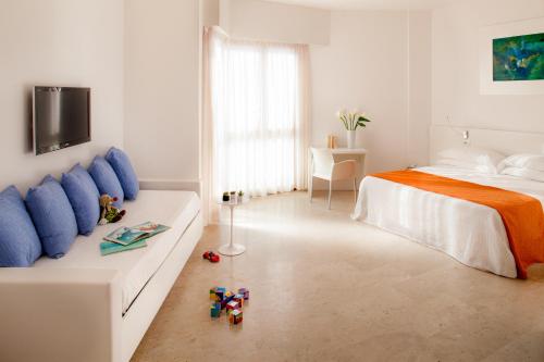 a white bedroom with a bed and toys on the floor at Hotel Caravelle Thalasso & Wellness in Diano Marina