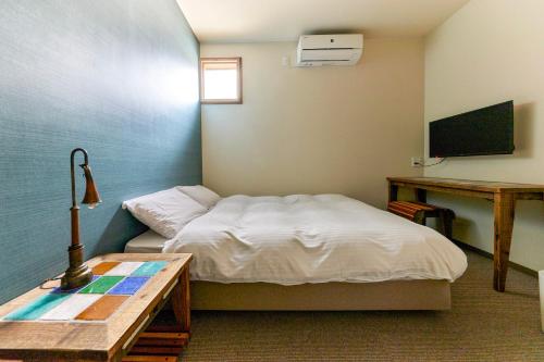a small bedroom with a bed and a table at HOTEL tuka miika in Ishigaki Island
