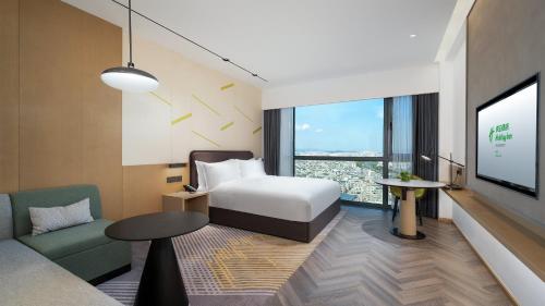 a hotel room with a bed and a couch and a tv at Holiday Inn Yongkang in Jinhua