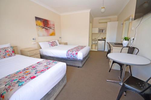 a hotel room with two beds and a table at Ben Chifley Motor Inn in Bathurst