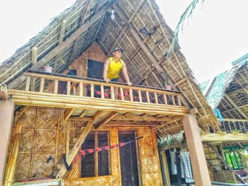a man standing on the balcony of a house at Titaays Surfers Inn in Baras