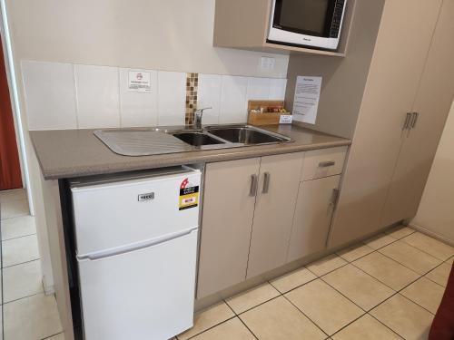 a kitchen with a white refrigerator and a sink at Charters Towers Motel in Charters Towers