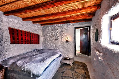 a bedroom with a bed in a stone wall at Aspros Potamos in Makry Gialos