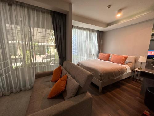 a bedroom with a bed and a couch and a window at Phuket apartment surin beach in Thalang
