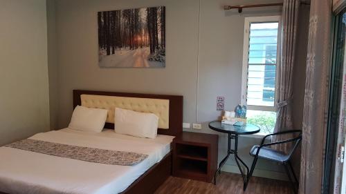 a bedroom with a bed and a table and a window at ที รีสอร์ท T Resort Suphanburi in Ban Noi