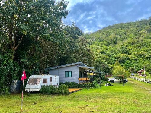 una pequeña casa en un patio con un remolque en Naramountainkhaoyai รถบ้าน, en Ban Tha Chang