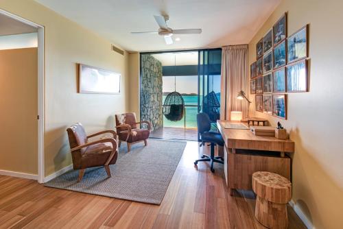 a home office with a desk and chairs and a table at Edge Apartments on Hamilton Island by HIHA in Hamilton Island