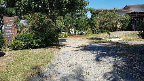 a dirt road in front of a building with a sign at ที รีสอร์ท T Resort Suphanburi in Ban Noi