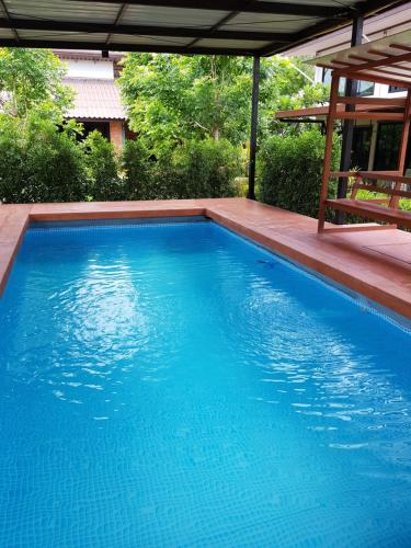a large blue swimming pool with a pergola at ที รีสอร์ท T Resort Suphanburi in Ban Noi