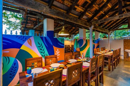 un comedor con mesas y sillas y una pared colorida en Zostel Plus Wayanad, en Kalpetta