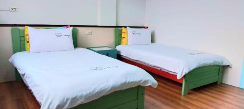 two beds in a room with white and green at 站前海民宿 in Hualien City