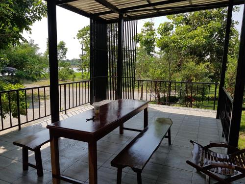 a wooden table and bench on a porch with a view at ที รีสอร์ท T Resort Suphanburi in Ban Noi