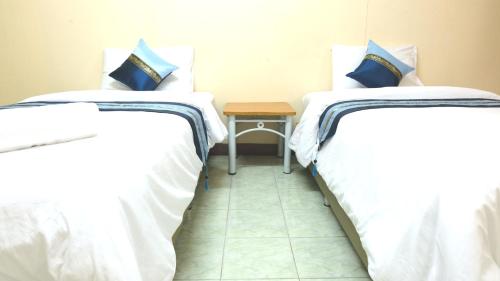 two beds in a room with a table between them at Goody Hotel in Bangkok