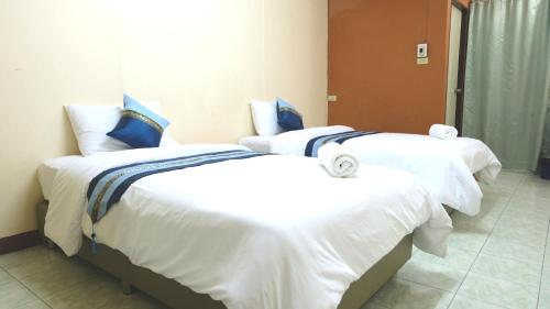 two beds in a room with white sheets and blue pillows at Goody Hotel in Bangkok