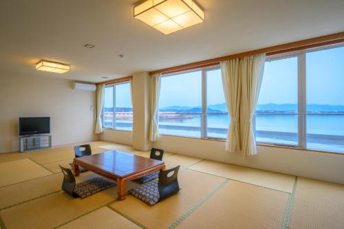 a large room with a table and chairs and windows at Kunibiki in Izumo