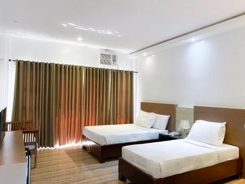 a hotel room with two beds and a window at Casa De Española Hotel and Resort in Aritao