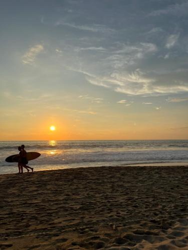a couple of people walking on the beach with a surfboard at Casa Karma in Puerto Escondido