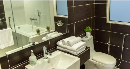 ein Badezimmer mit einem Waschbecken, einem WC und einem Spiegel in der Unterkunft Encorp Marina Suites near Legoland in Nusajaya