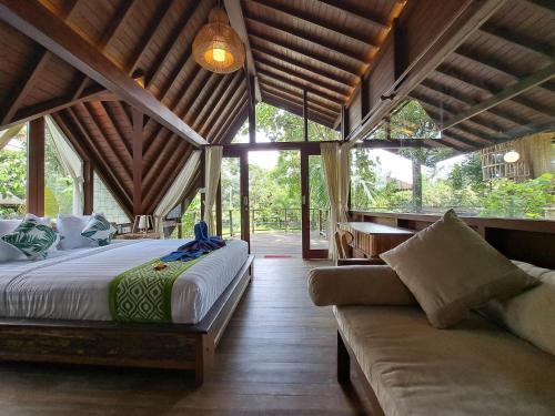 - une chambre avec un lit et un canapé dans l'établissement Green Tree House Villa Ubud, à Ubud