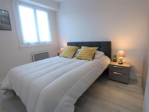 - une chambre avec un grand lit blanc et des oreillers jaunes dans l'établissement Appartement 3 étoiles à 150m de la plage du Letty, rénové, parking inclus - FR-1-481-97, à Bénodet