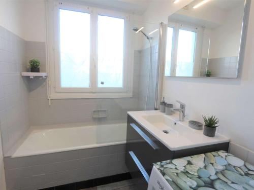 La salle de bains est pourvue d'un lavabo, d'une baignoire et d'une fenêtre. dans l'établissement Appartement 3 étoiles à 150m de la plage du Letty, rénové, parking inclus - FR-1-481-97, à Bénodet