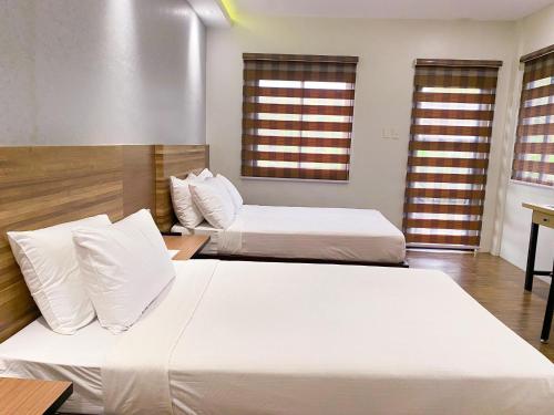 two beds in a room with two windows at Casa De Española Hotel and Resort in Aritao