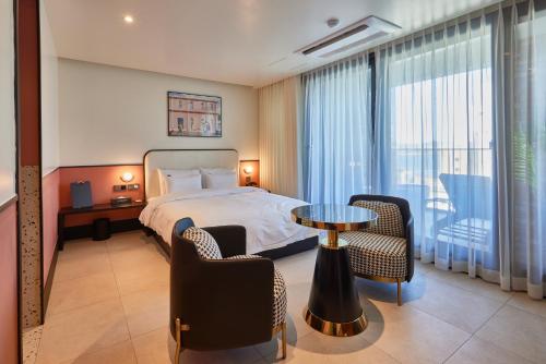 um quarto de hotel com uma cama, uma mesa e cadeiras em Browndot Terrace Pohang Passenger Terminal em Pohang